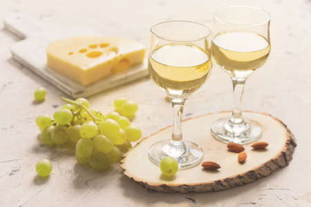 Two glasses of white wine with grapes, cheese and nuts.の写真素材
