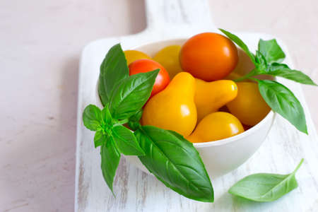 bowl with different cherry tomatoes and basil closeup.の写真素材