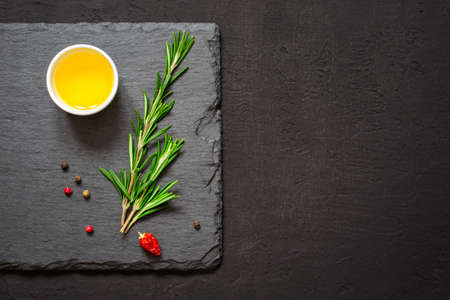 Sprigs of rosemary and olive oil on a cutting board. Top view with copy spaceの写真素材