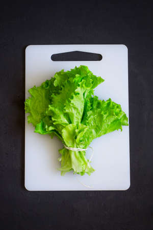 bunch of lettuce on a cutting board, top view.の写真素材