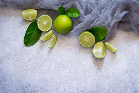 Concrete background with juicy limes. Top view with copy space.