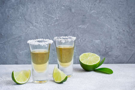 Mexican tequila gold in short glasses with salt and  lime slices, copy space 