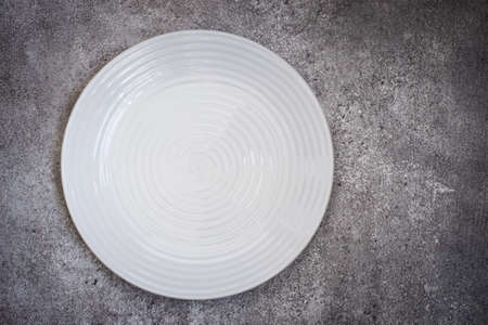 Empty white ceramic plate On a concrete background. Top view with copy spaceの写真素材