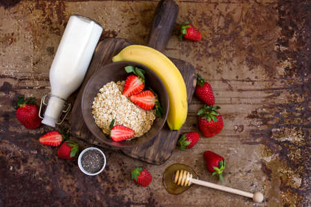 Healthy breakfast ingredients: Oatmeal, honey, fruit, strawberry and chia seeds. concept of natural organic foodwith. Top view with copy spaceの写真素材