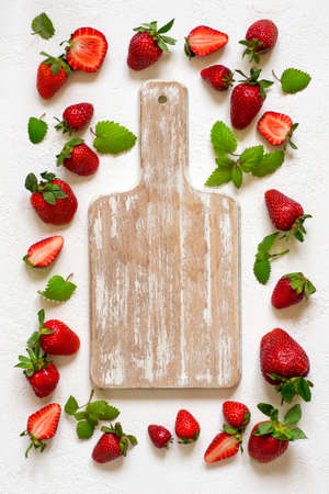 empty wooden cutting board on a white background in the orchid ripe strawberries and mint. Top view with copy spaceの写真素材