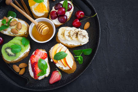 Assorted summer sweet snacks. Bruschetta or sandwiches with fruit and berries. Top view with copy spaceの写真素材