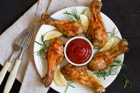 Roasted chicken drumstick in red sauce Basil and lemon on a black background. Top viewの写真素材