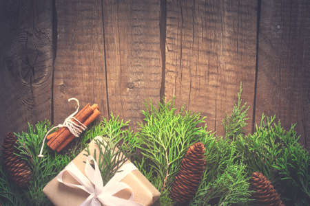 Natural Christmas New Year background. Coniferous branches with cones on old wooden boards. Toned