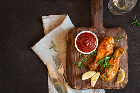 Grilled spicy chicken drumstick is served on a wooden board. Top view with copy spaceの写真素材