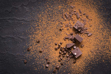 Chocolate background. Pieces and drops of chocolate, cocoa powder on black.の写真素材