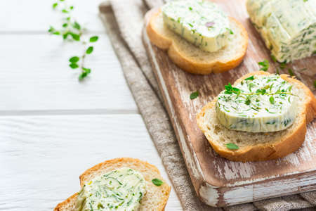 Sandwiches with herbs butter On Cutting board on white wooden background.の写真素材