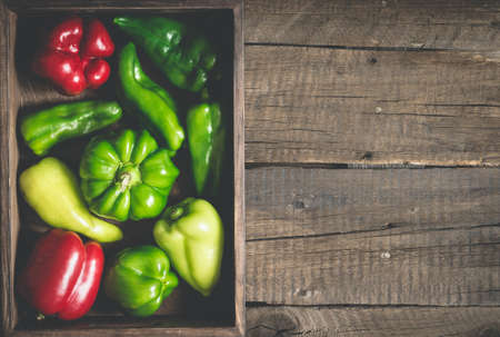 variety red and green bell peppers of various shapes. Full vegetable tray On a wooden background.の写真素材