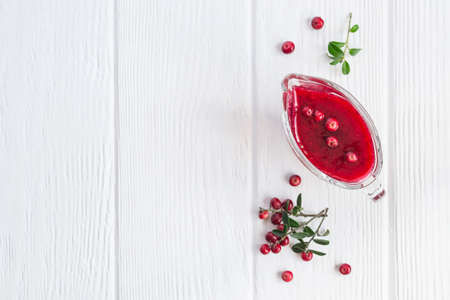 Fresh Lingonberry sauce in a gravy boat On a white wooden background. Top view with copy space.の写真素材