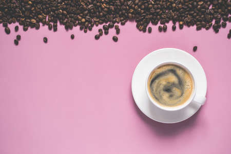 cup of coffee with foam and beans on a pink background.の写真素材