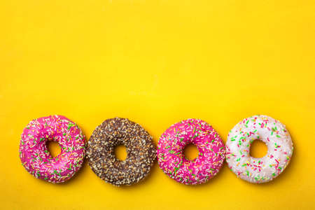 Four donuts in line on yellow background. Top view with copy spaceの写真素材