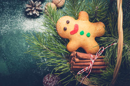 Christmas card with gingerbread man and coniferous branches in basket.