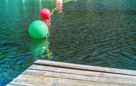Multicolored buoys on dark little wavy water. warning Sign for swimmers.の写真素材