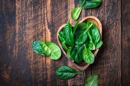 Baby spinach leaves in a bowl on dark background.の写真素材