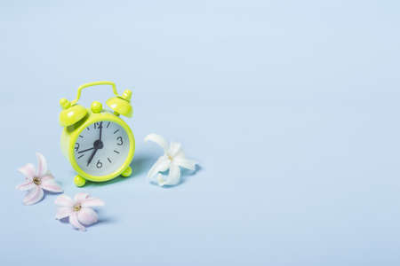 Spring Flowers and alarm clock. Springtime concept.