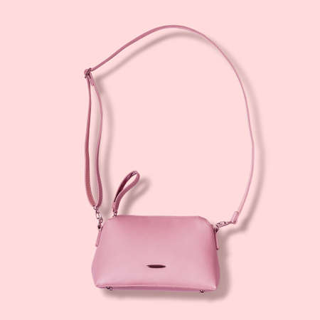 Ladies pink pastel handbag with long strap on pink background.の写真素材