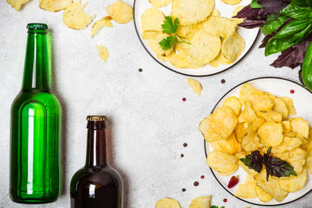 Crispy potato chips and and beer bottles on a gray background.の写真素材