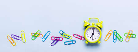 School supplies and alarm clock on a blue background. Back to school concept.