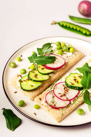 Healthy sandwiches with soft cheese and raw vegetables on crisp bread.