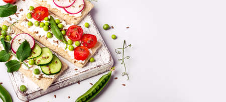 Healthy sandwiches with soft cheese and raw vegetables on crisp bread.