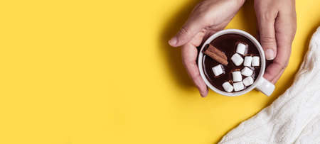 Female hands hold a thick hot chocolate cup.