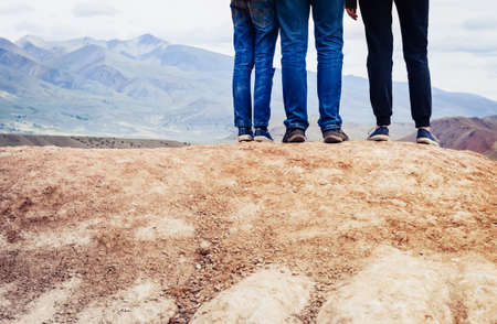 group or family of tourists is standing on a hill. Legs of travelers close-up.