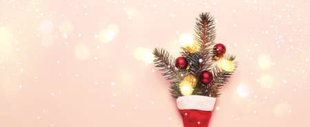 Christmas shining lights bokeh background. Fir branches and red balls in Santa hat.