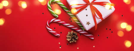 Christmas gift box and candy cane with shining lights on red background.の写真素材