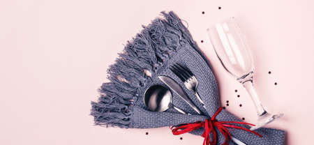Champagne glass, cutlery and napkin on pink pastel background. Long banner format.の写真素材
