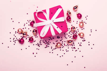 Christmas gift and balls with confetti on pink pastel background.の写真素材