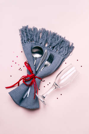 Christmas Table Setting. Champagne glass, cutlery and napkin on pastel background.