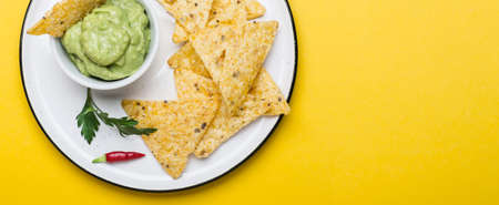 Traditional Latinamerican Guacamole With Corn Chips Nachos on yellow background. Banner format.の写真素材