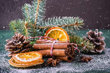 Christmas greeting card with cinnamon, dry oranges and spruce branches.