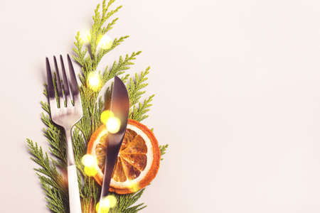 Christmas table setting concept. Fork and knife decorated with thuja twig and bokeh lights.の写真素材