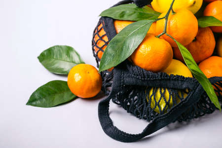 Tangerines and lemons in textile bag on gray background. Healthy food and zero waste concept.の写真素材