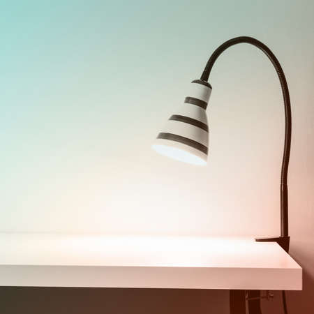 Luminous striped lamp on white table. White wall for mock up. Pastel toning.の写真素材