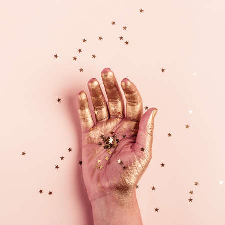 Female golden hand with golden stars closeup. Art Creativity Concept.