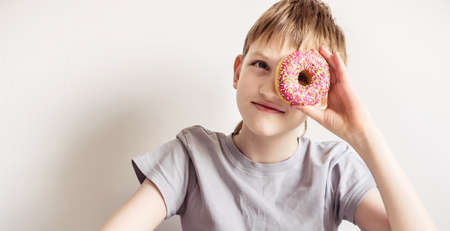 Teen boy looking into hole from glazed donut.の写真素材