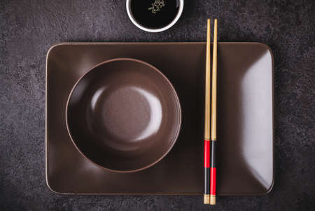 Asian table setting. Brown bowls, soy sauce and bamboo chopsticks.の写真素材