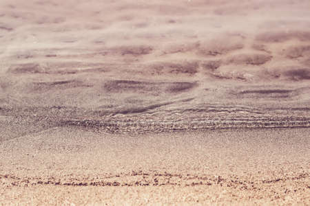 Silent transparent waves and sandy beach close-up. Summer and travel concept.