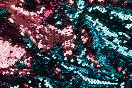 Festive  made of turquoise and pink sequins. Shiny fabric texture.の写真素材
