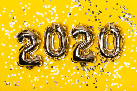 Golden foil balloons on yellow  with sparkles.の写真素材