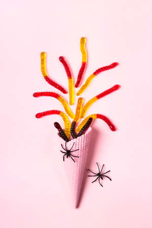 Pink ice cream cone with colorful marmalade worms and spidersの写真素材