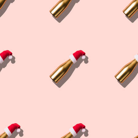 Seamless Christmas texture made of Golden champagne in Santa hat on pink