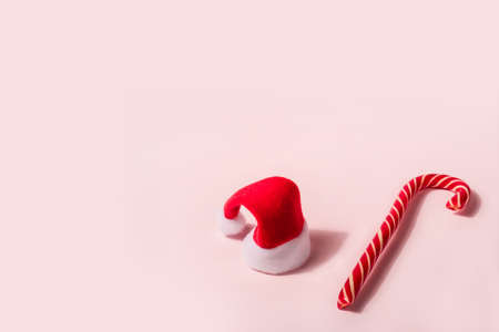 Trendy Christmas background with Santa Claus hat and candy cane. Minimal Christmas concept.の写真素材