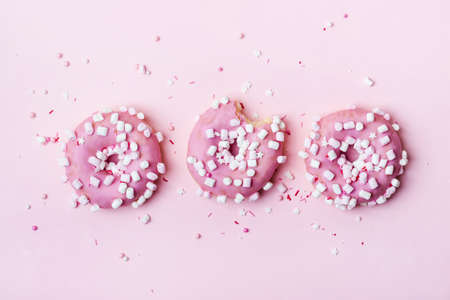 Creative layout made of pink donuts with marshmallows and sprinkled. Food concept.の写真素材